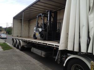 nissan forklift being loaded onto truck for delivery